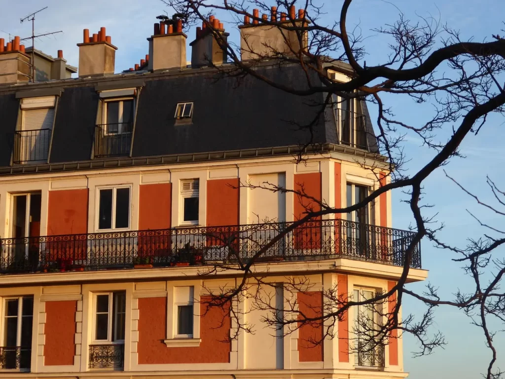 Une élégante façade d’immeuble, baignée par la lumière dorée du soleil couchant, illustre le charme et le prestige de l’immobilier dans une ville française.